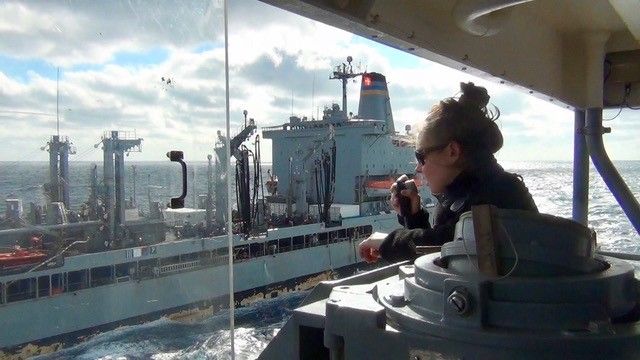 Female seafarer looking at a passing ship from her own vessel