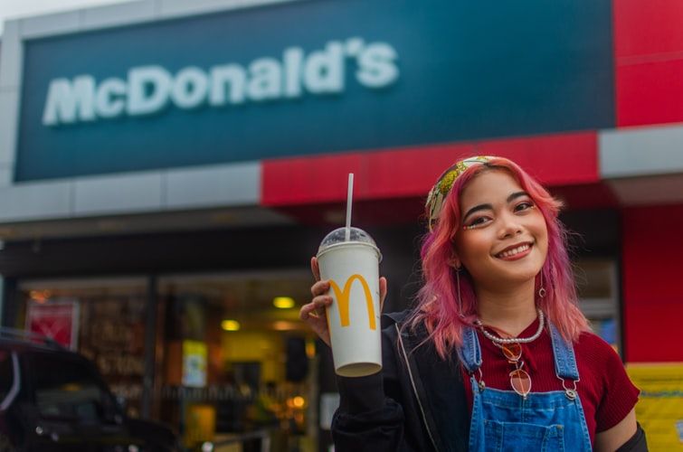 Young woman lifting up a McDonald's cup outside the restaurant