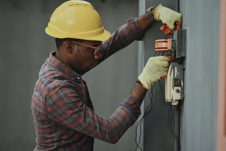 Electrician fixing some equipment mounted on a wall