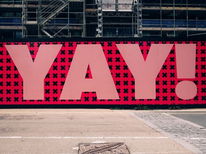 The word 'yay!' in giant pink letters on a wall