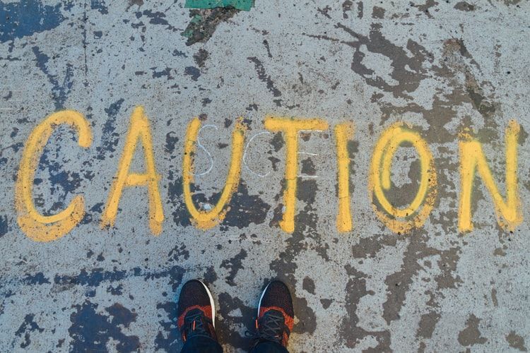 The word caution spray painted on the ground on yellow