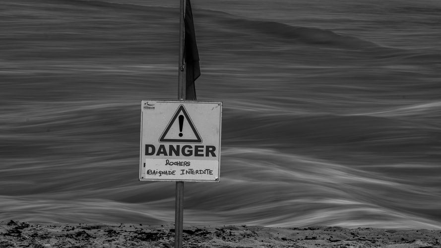 Grey stormy sea and a danger sign on the beach