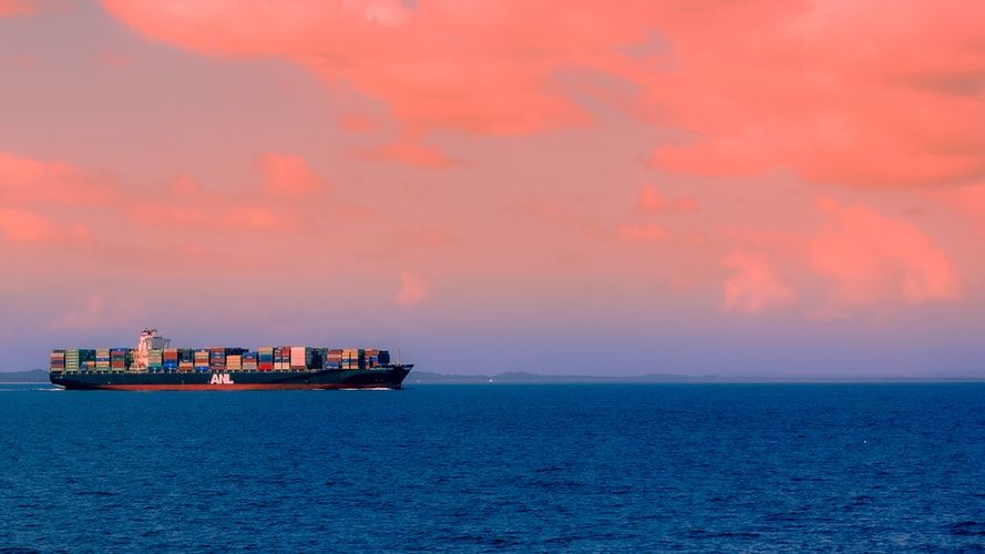 A container ship sailing beneath a pink cloudy sky