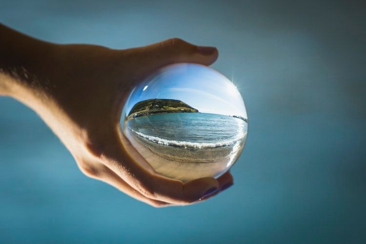 Hand holding a glass globe with an image of the sea in it
