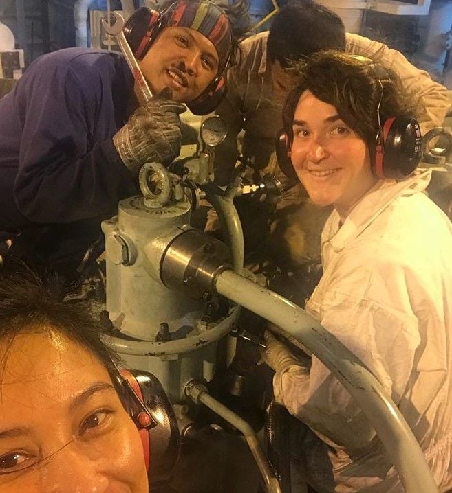 Smiling group of seafarers working on an engine