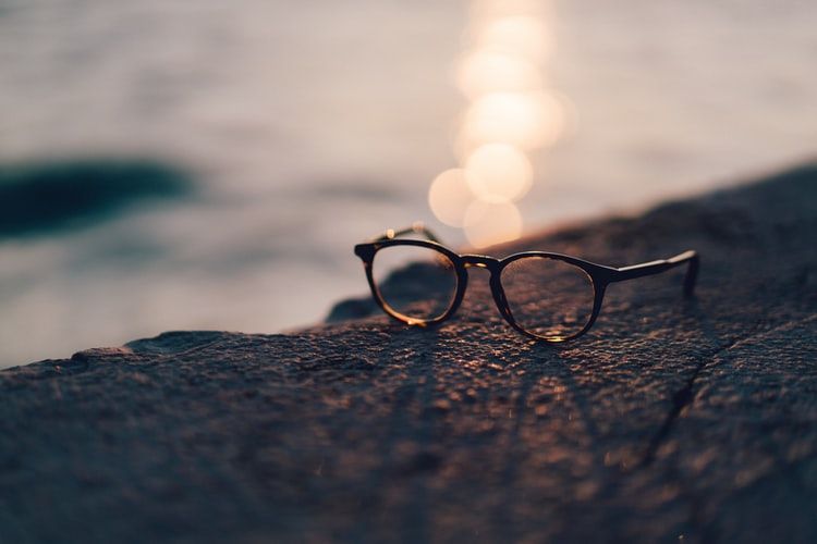 A pair of glasses sitting on a wall overlooking water
