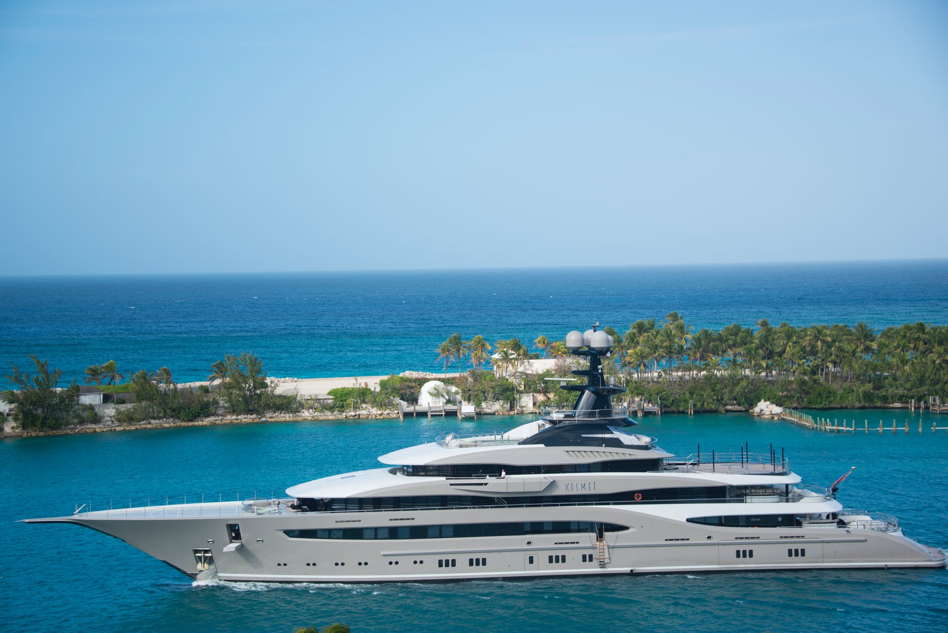 A superyacht sailing past a sandbank with palm trees