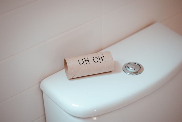 Empty toilet roll on a cistern with 'uh oh!' written on it