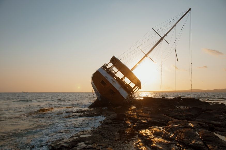 A capsized boat leaning against rocks