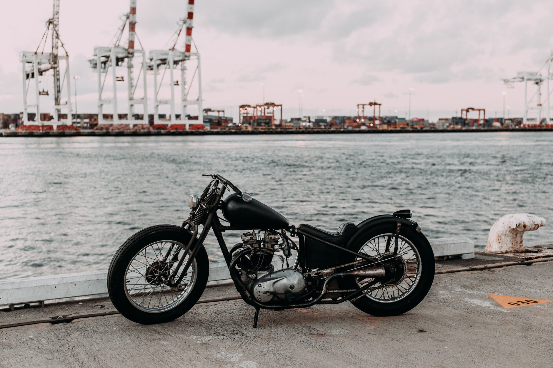 Motorcycle standing on a dock overlooking a port