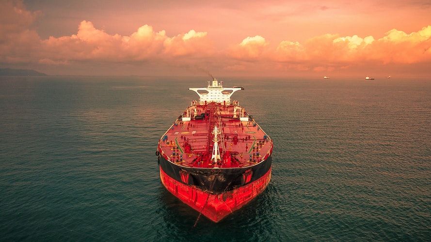A red tanker sailing towards the camera at sunset