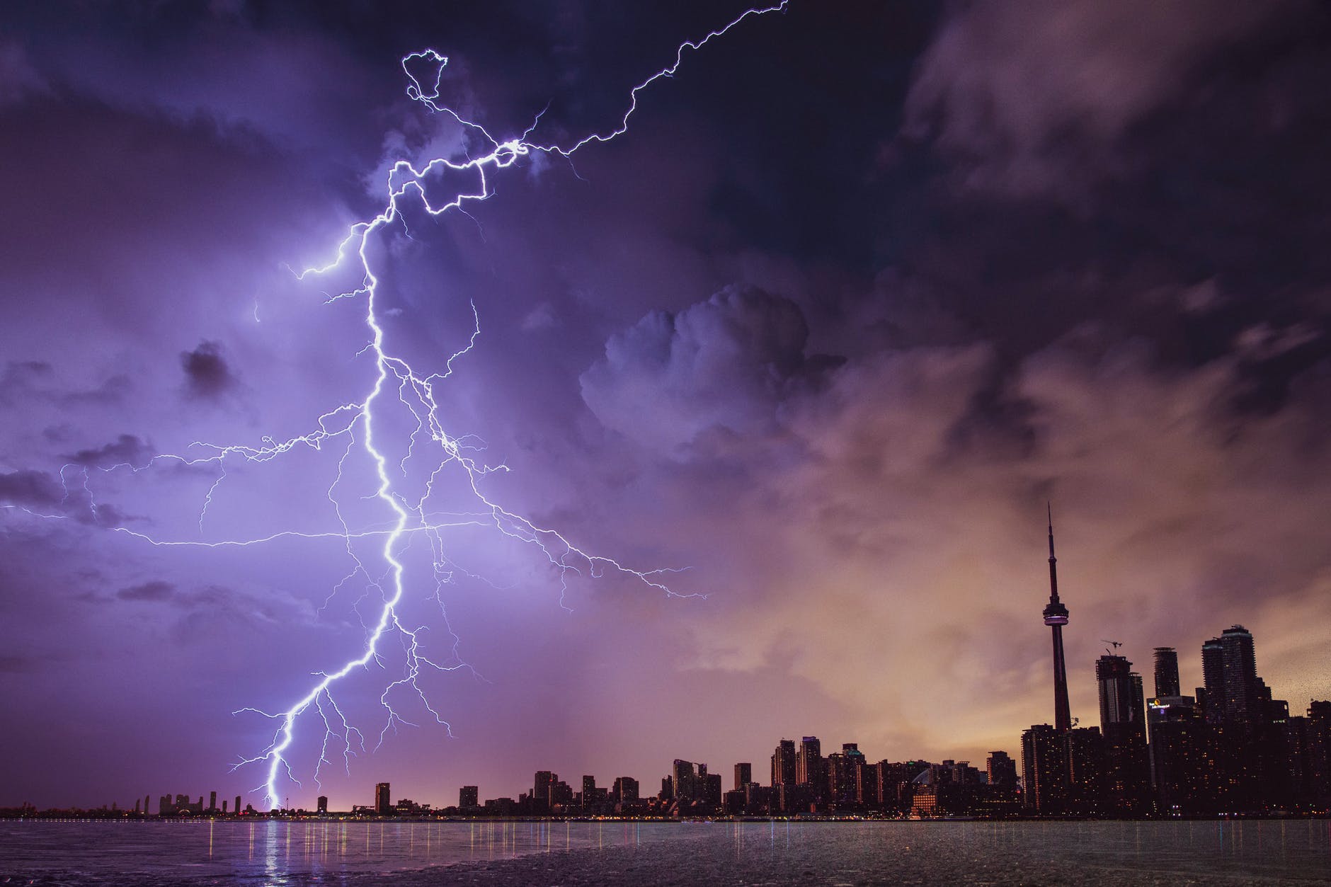Forked lightning over a city skyline next to water