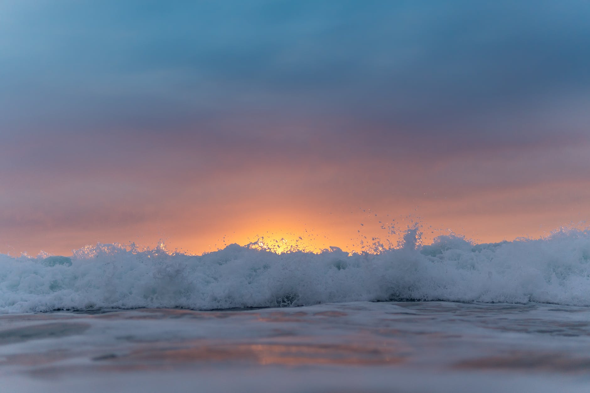 Surf crashing on the shore at sunset