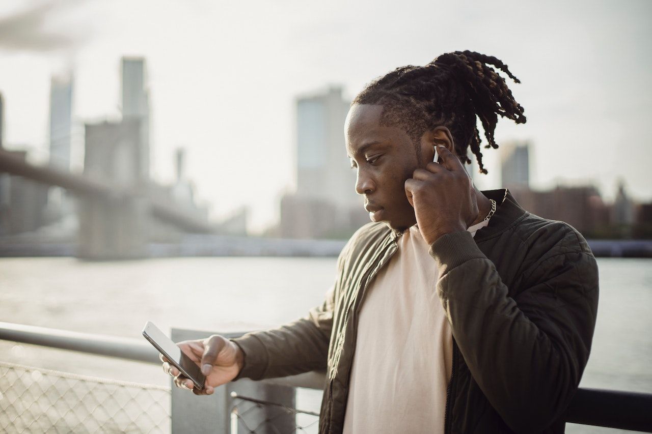 man looking at phone wearing earbuds