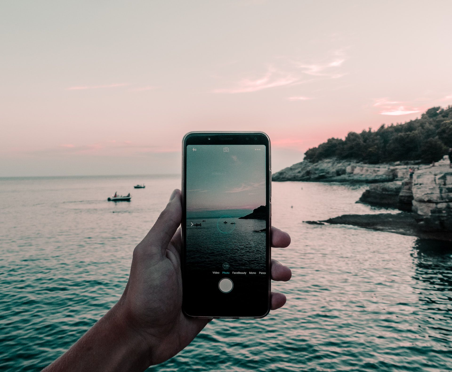 hand holding phone in front of ocean