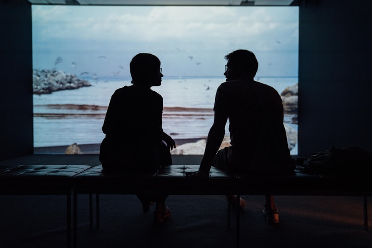 The silhouettes of two people talking in front of an ocean