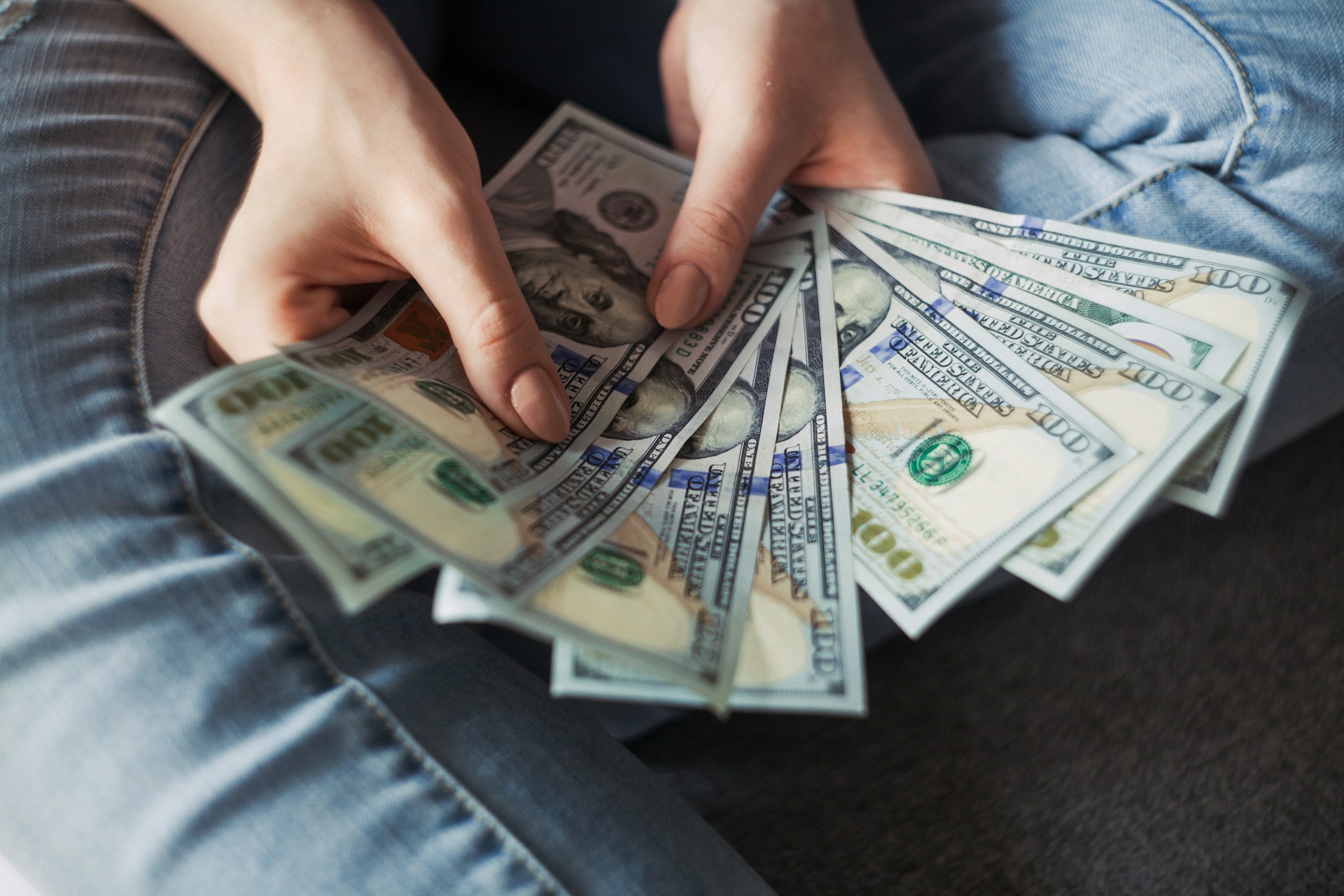 a person holding a fan of dollar bills