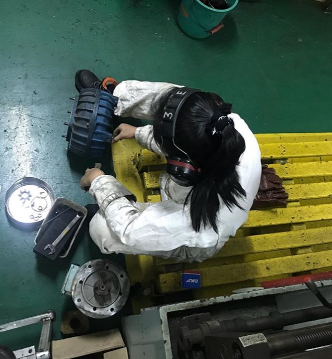 A female seafarer working in a job at sea that involves repairing machinery 