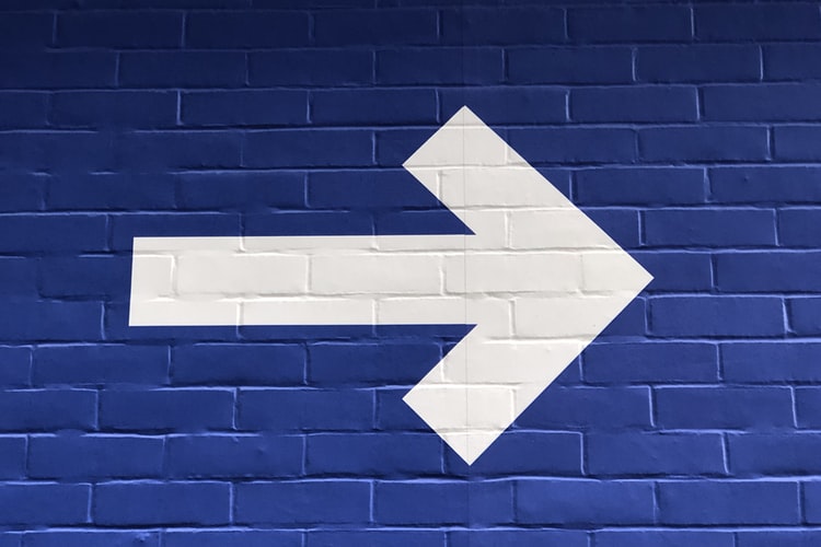 white arrow on a blue wall pointing right