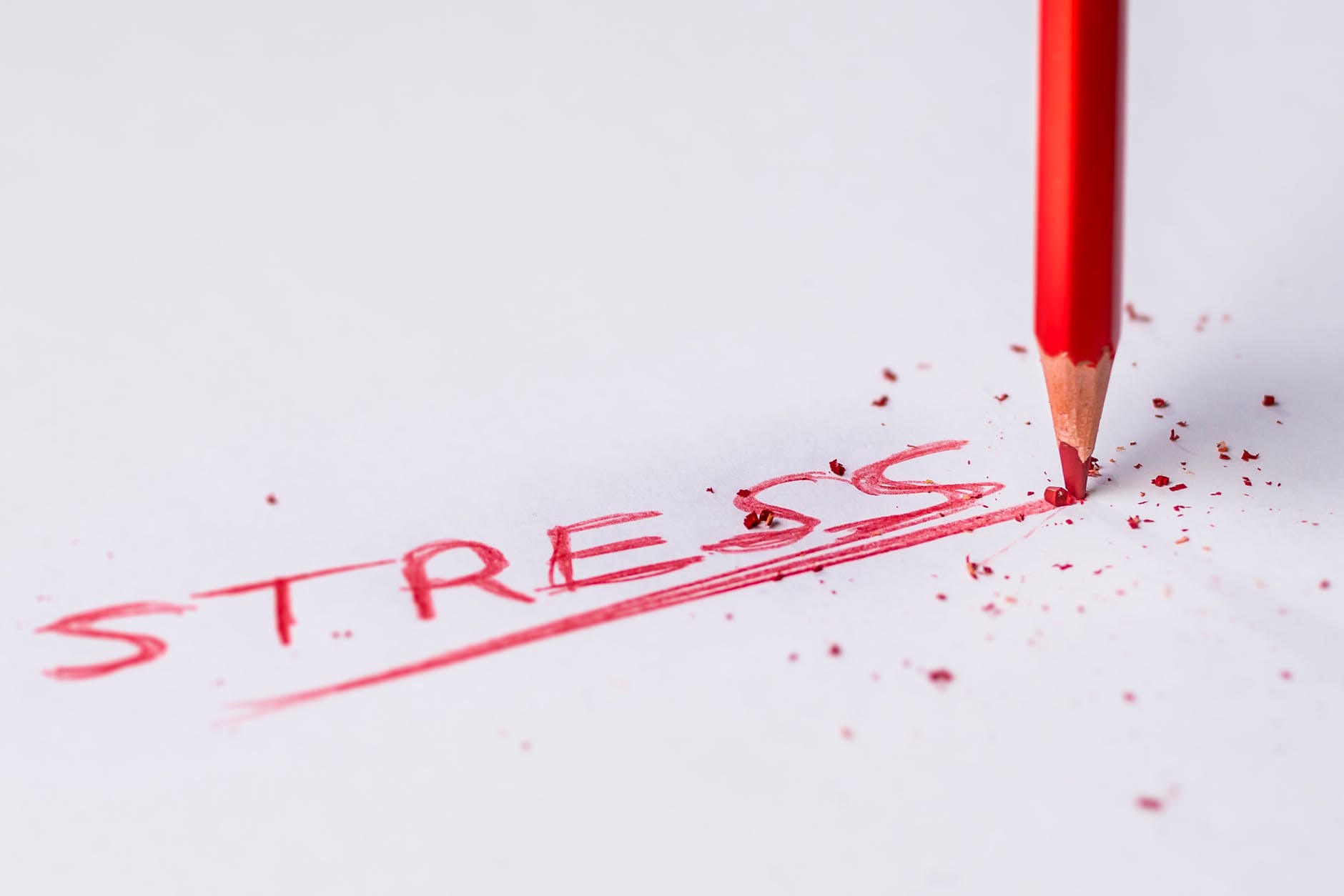 A red pencil writing the word 'stress' and snapping under the pressure
