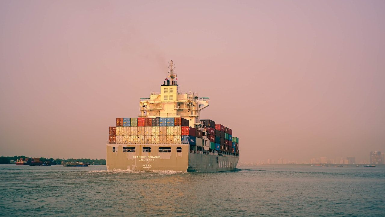 A container ship sailing into a pink sunset