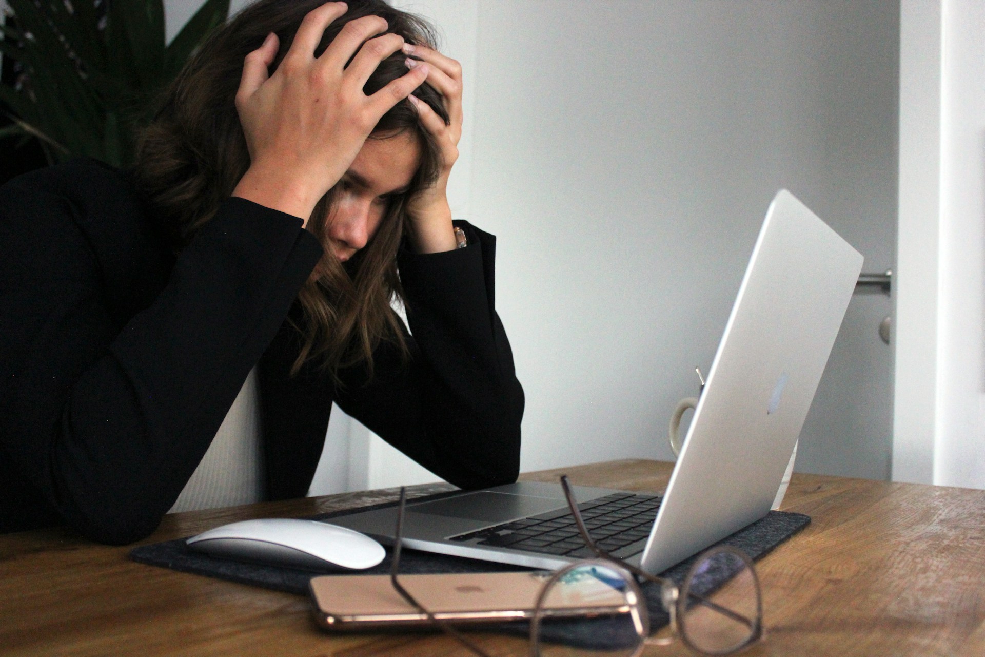 Frustrated woman with her head in her hands using a laptop