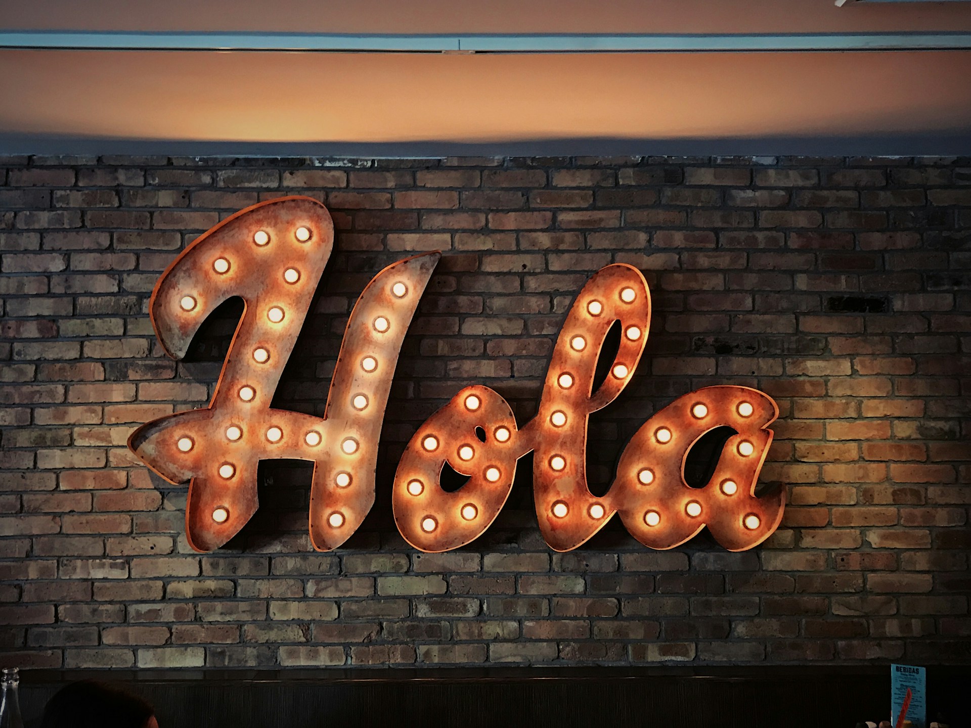 metal sign with lightbulbs on it saying 'hola'