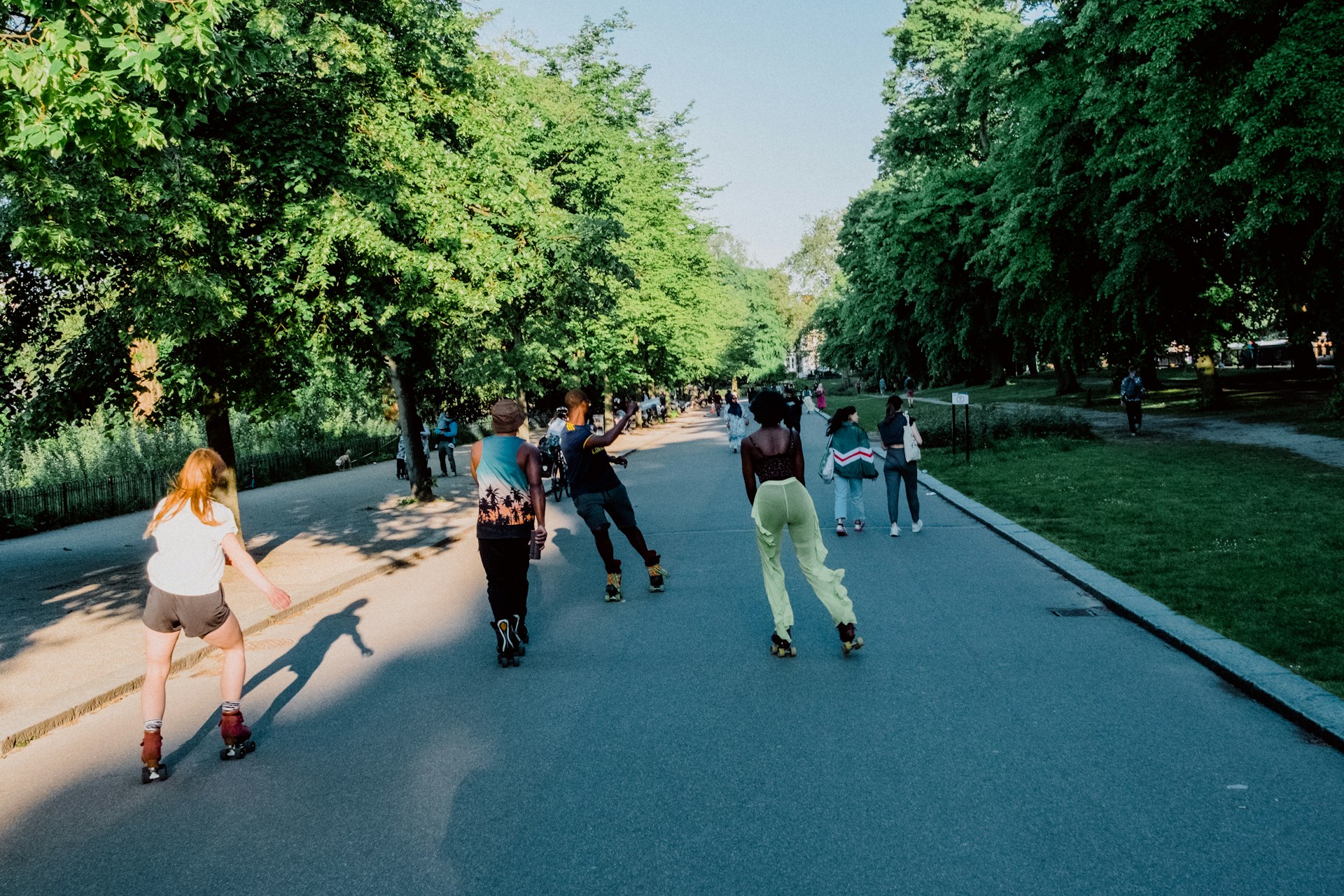 A group of people roller skating through a park
