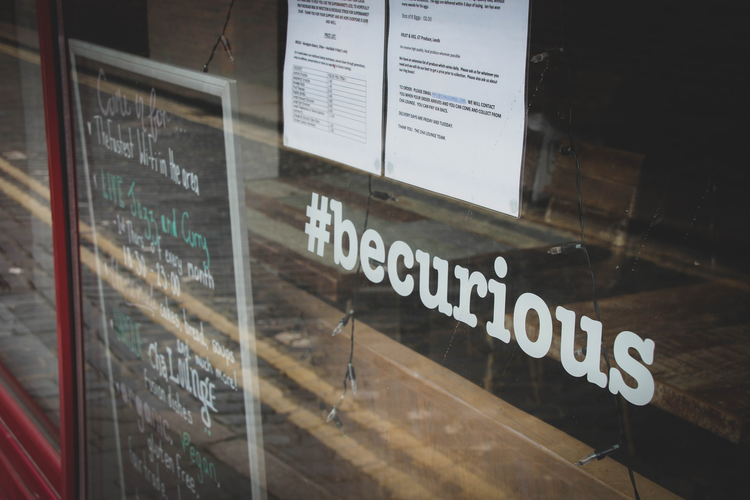 a sign on a window saying 'be curious'