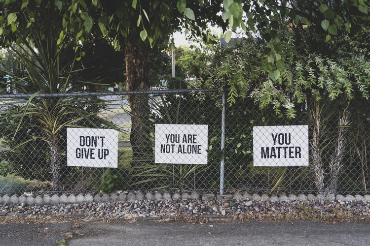 three motivational signs on a chain link fence