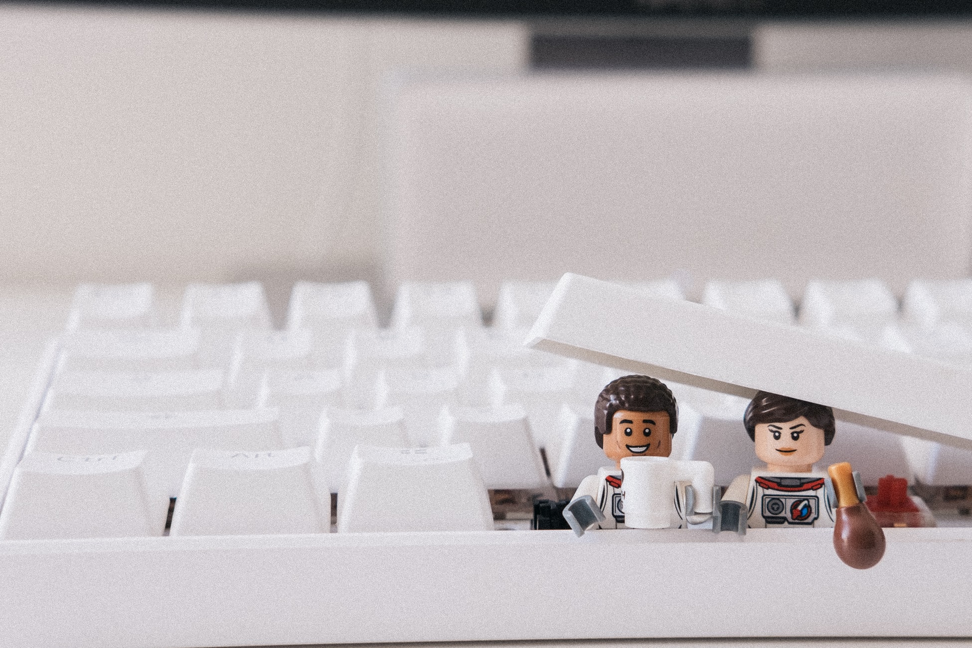 two Lego figured popping up from under the space bar on a keyboard