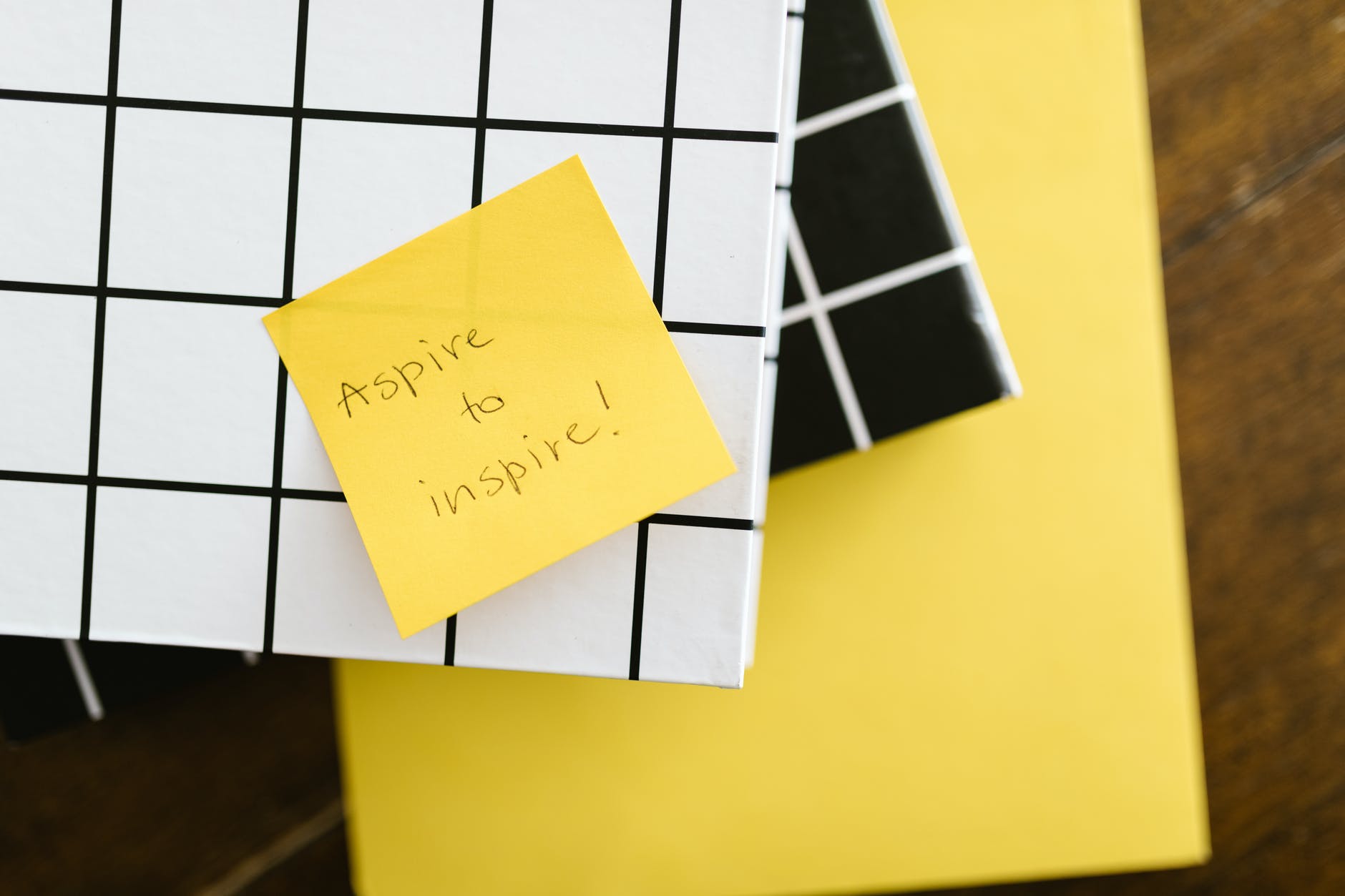 a post-it stuck on a laptop saying 'aspire to inspire'