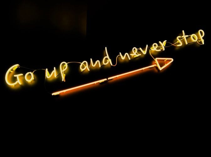 neon sign saying go up and never stop