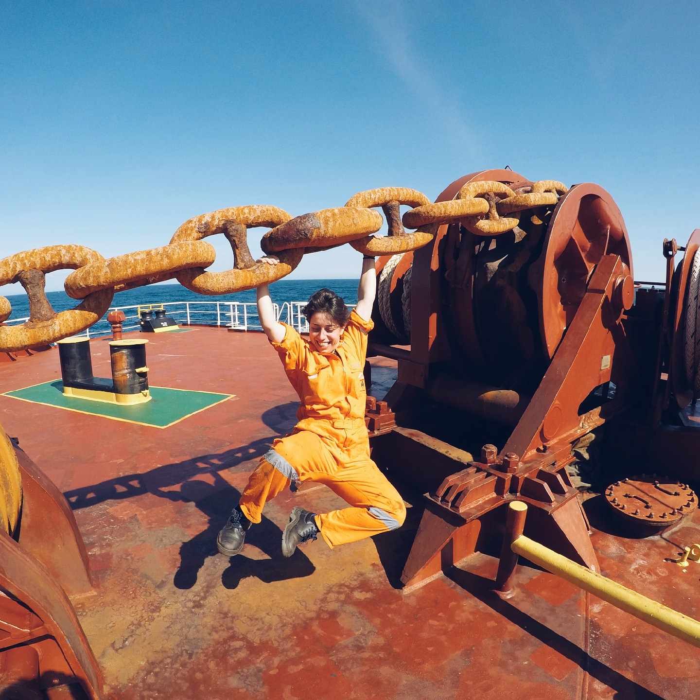 a female seafarer having fun swinging on the anchor chain while working on a cargo ship