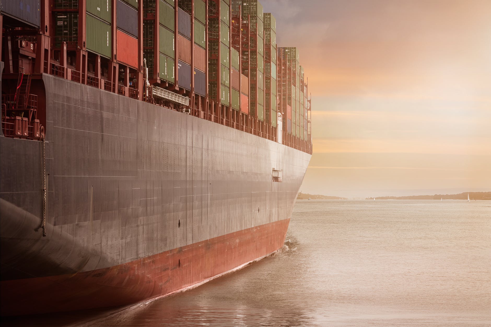 the hull of a container ship as it sails into sunset