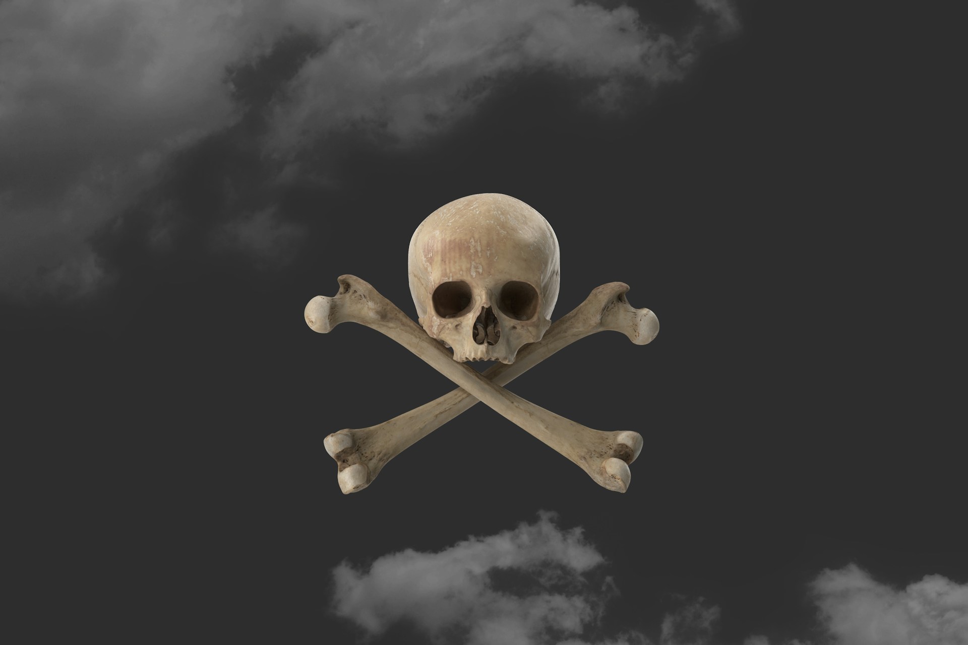 a skull and crossbones against a black, cloudy sky