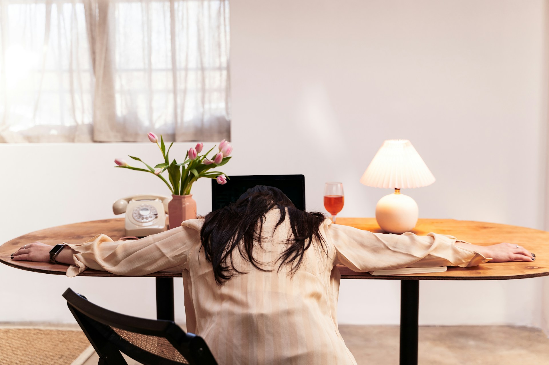 a woman with her head on her desk in front of her laptop