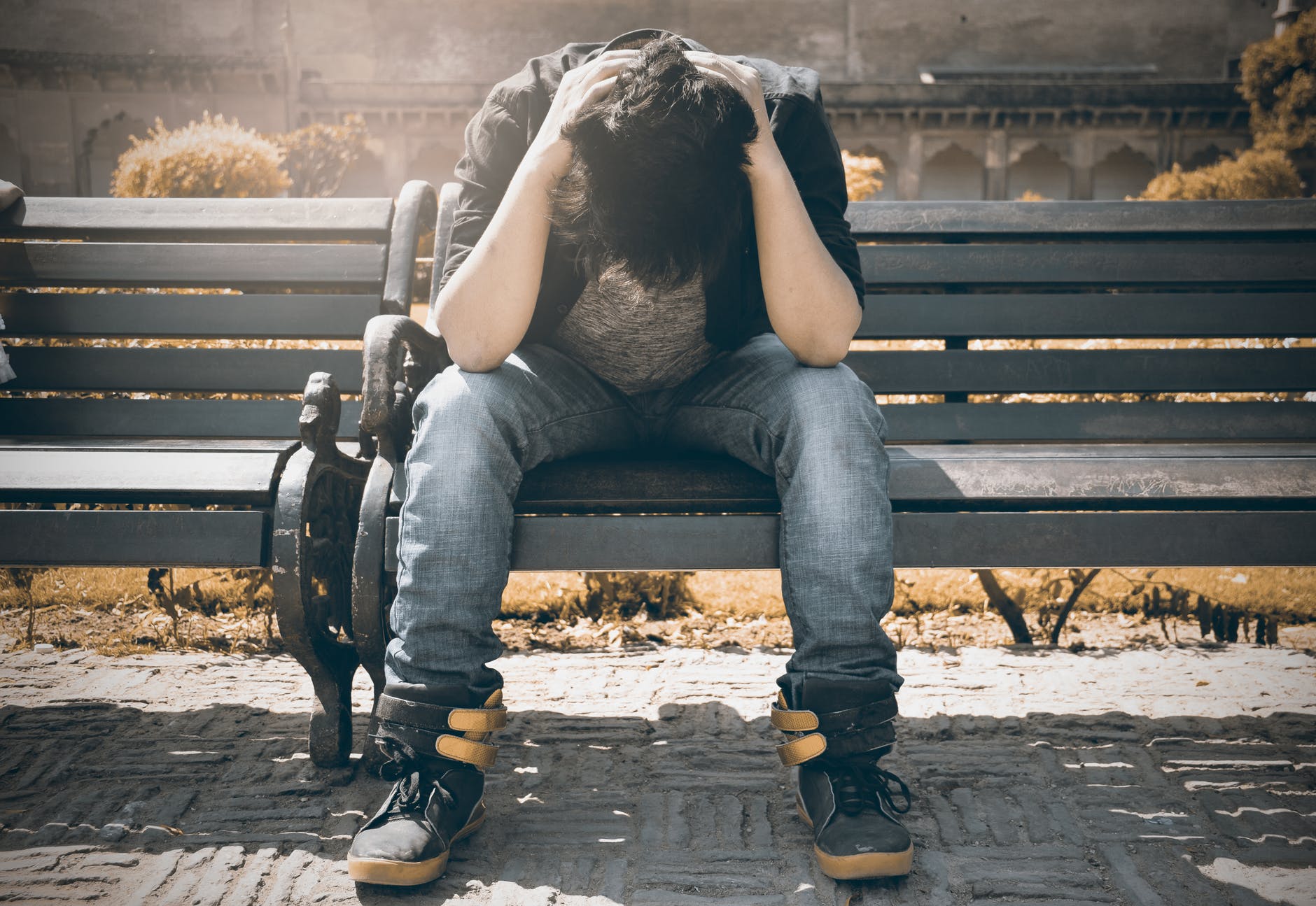 man sitting on a bench with his head in his hands