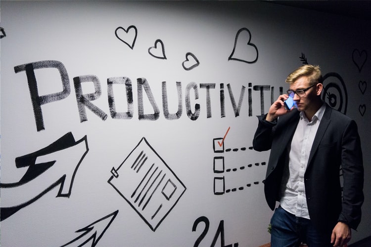 A businessman standing next to a whiteboard with the word 'productivity' on it