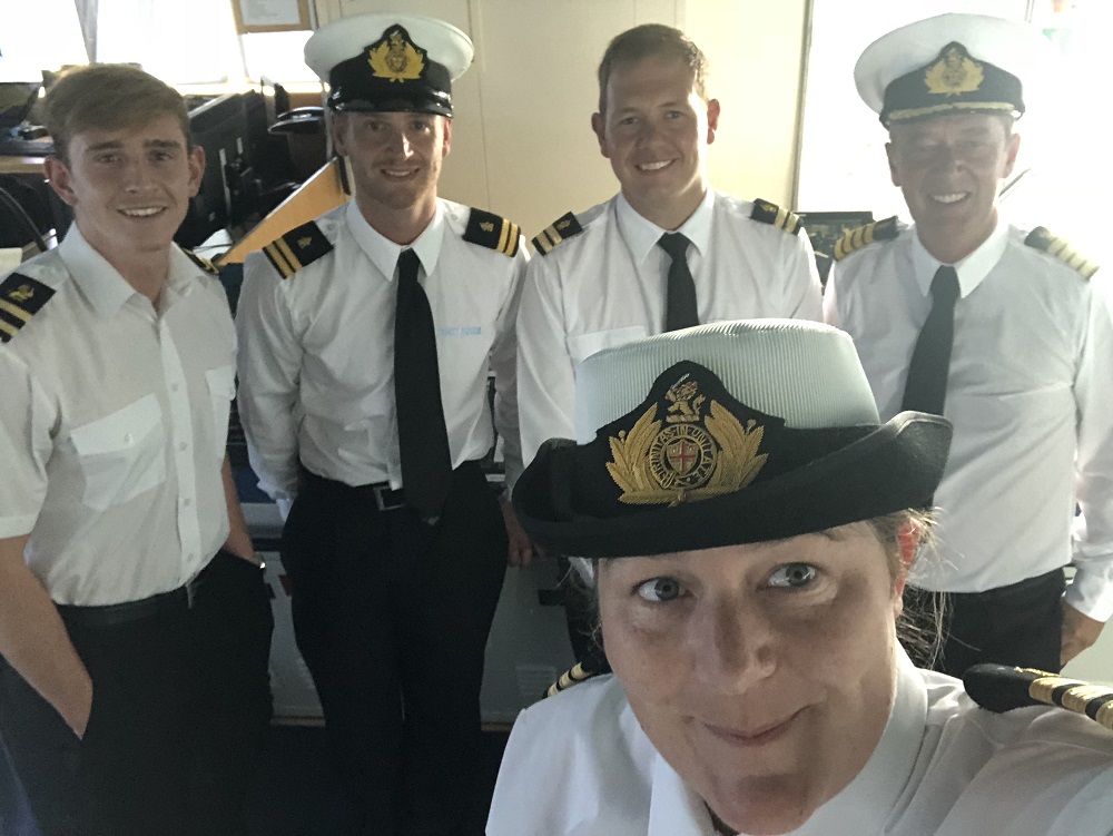 a group of officers working in seafarer jobs taking a selfie as they work on a ship