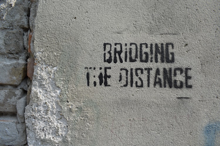 stenciled sign on a wall saying 'bridging the distance'