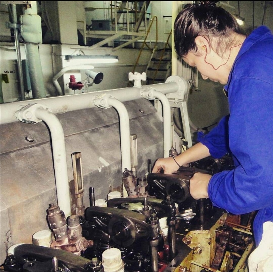 A female seafarer checking machinery while working on a cargo ship