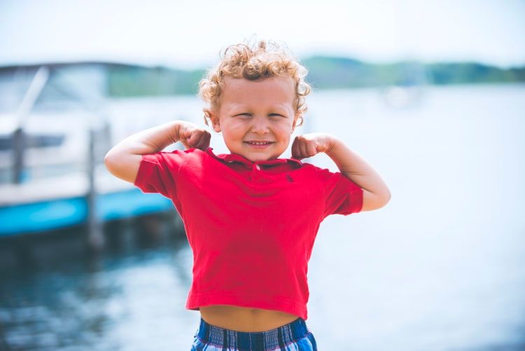 little boy on dock flexing his muscles