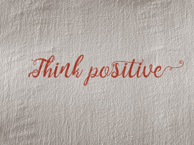 The words 'think positive' painted on a wall