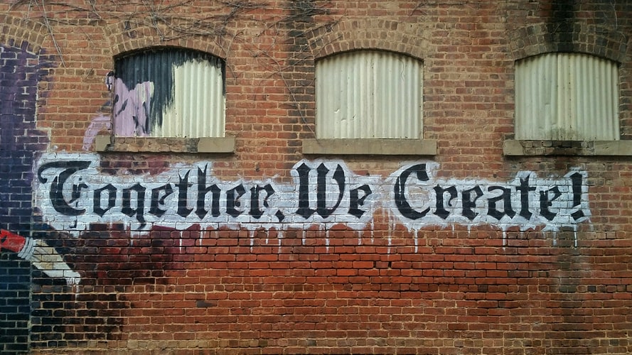 Graffiti on a wall saying 'together we create'