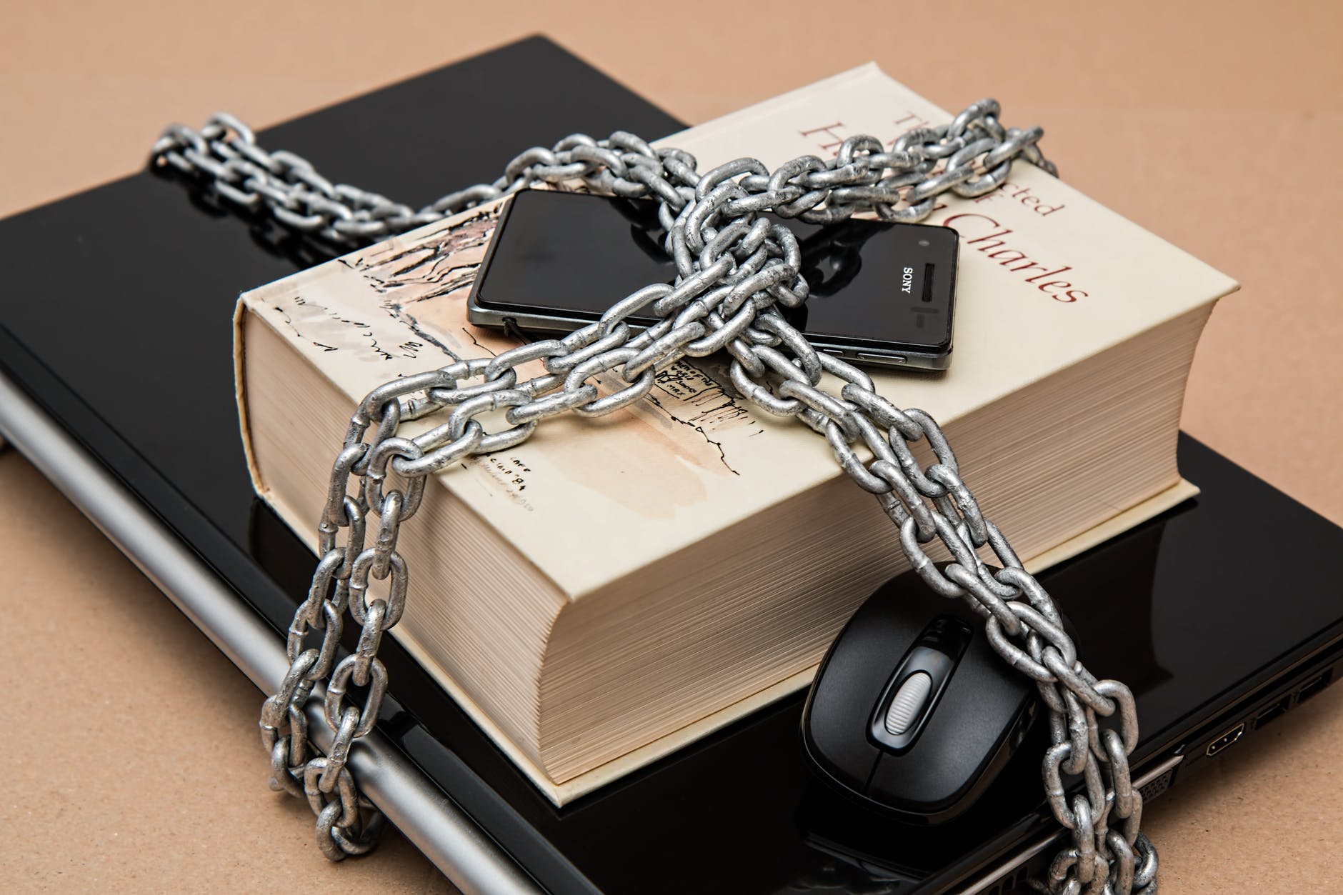 a laptop, book and mouse wrapped in chain