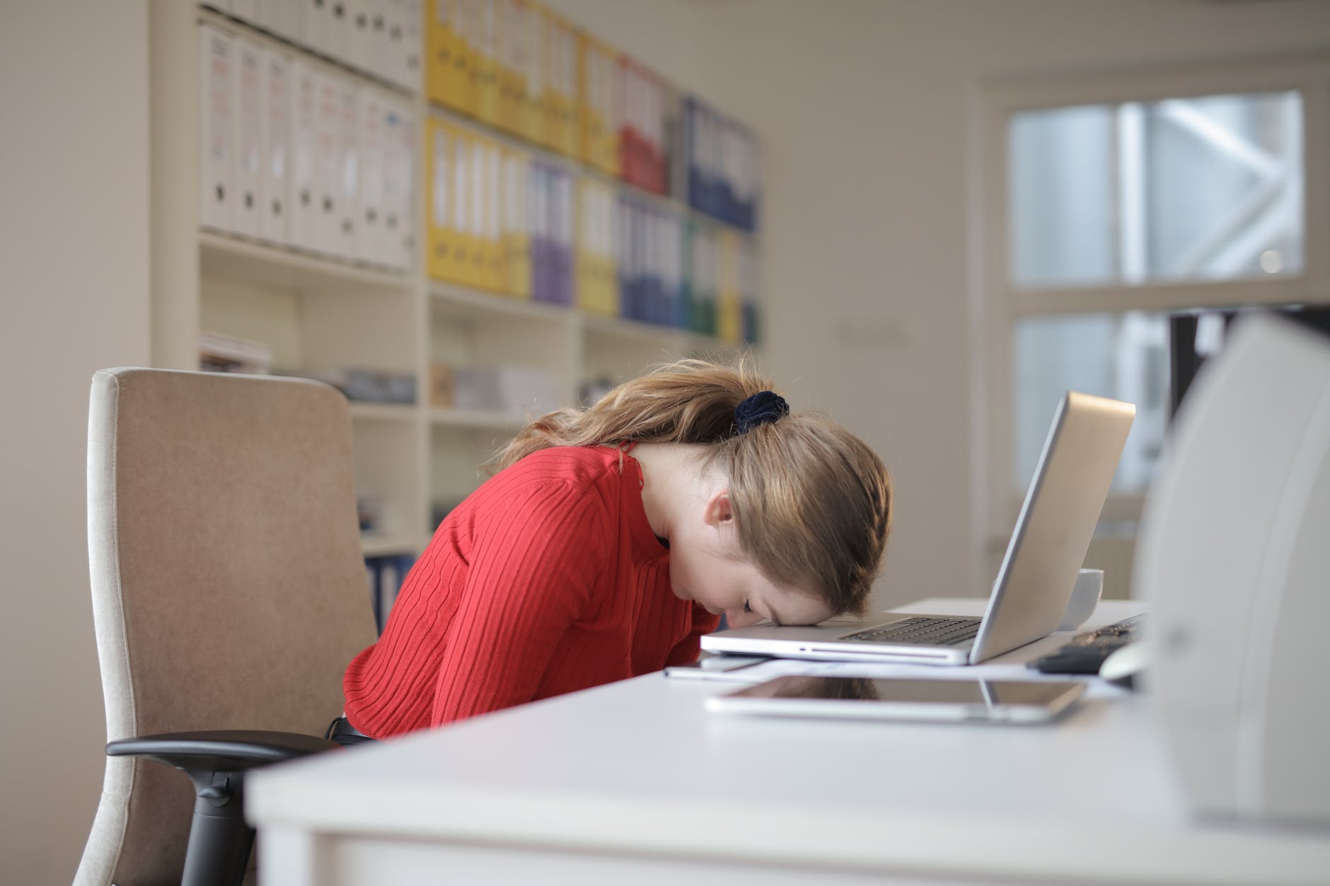 Woman with her head resting on her desk in defeat