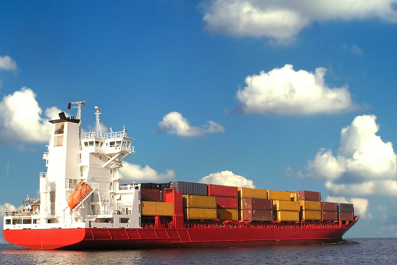 a red and white cargo ship under a blue sky