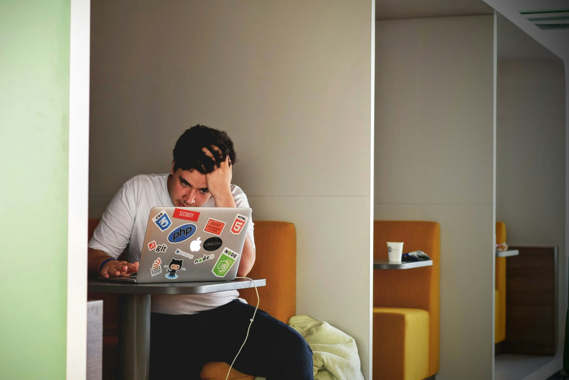 man with his head in his hands using his laptop