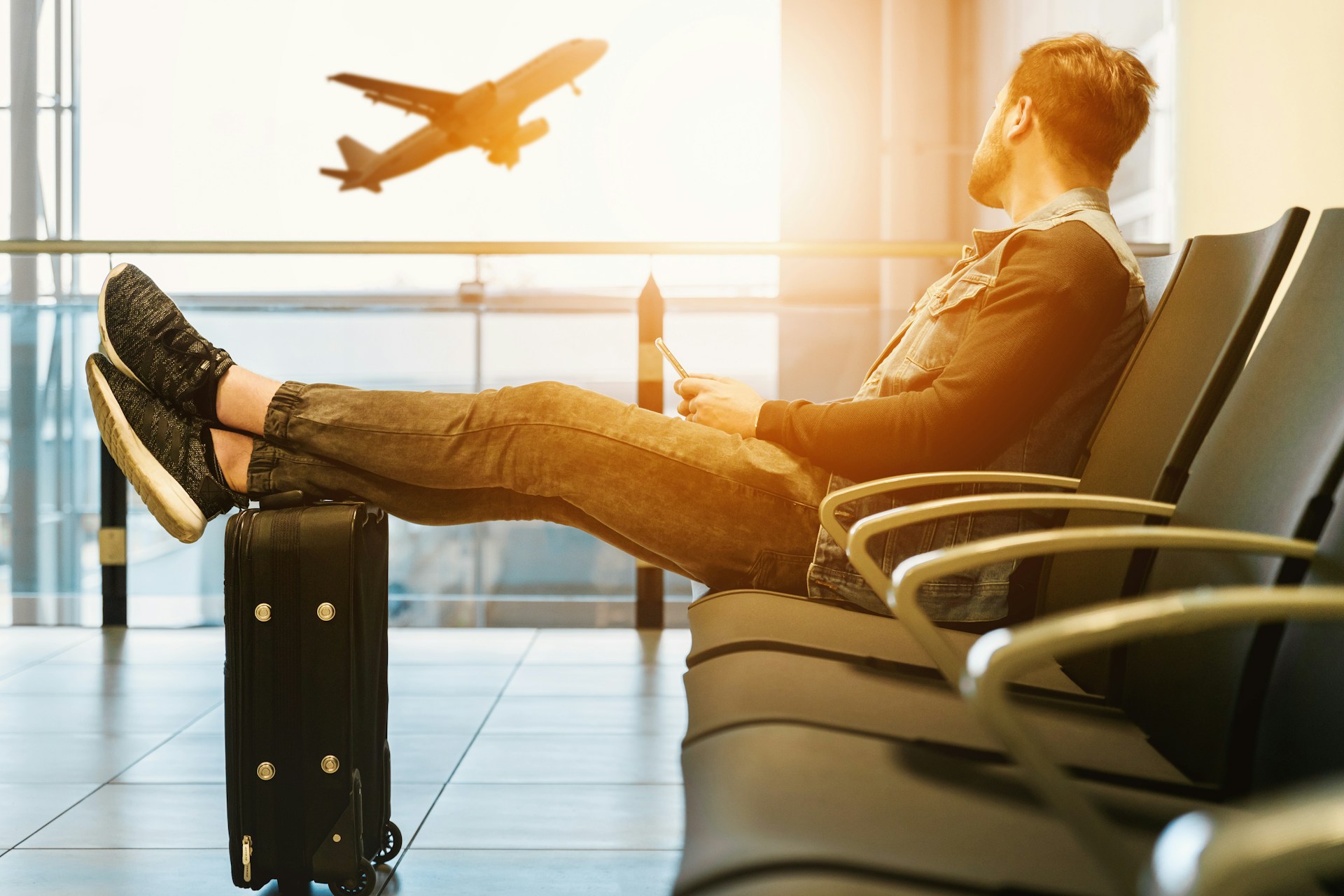 A man in an airport watching a plane take off